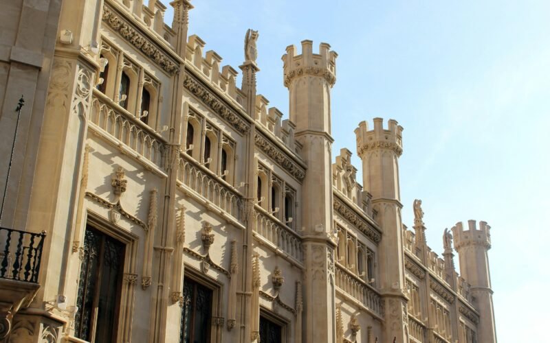 Beige Betongebäude während des Tages auf Mallorca, fotografiert von L'Odyssée Belle.