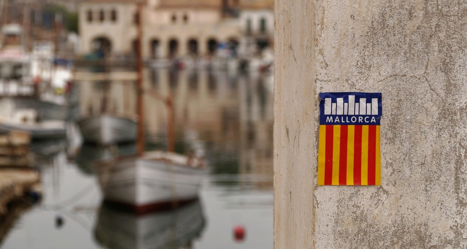 Sticker an einer Wand nahe einem Hafen auf Mallorca, aufgenommen von Alex Kulikov