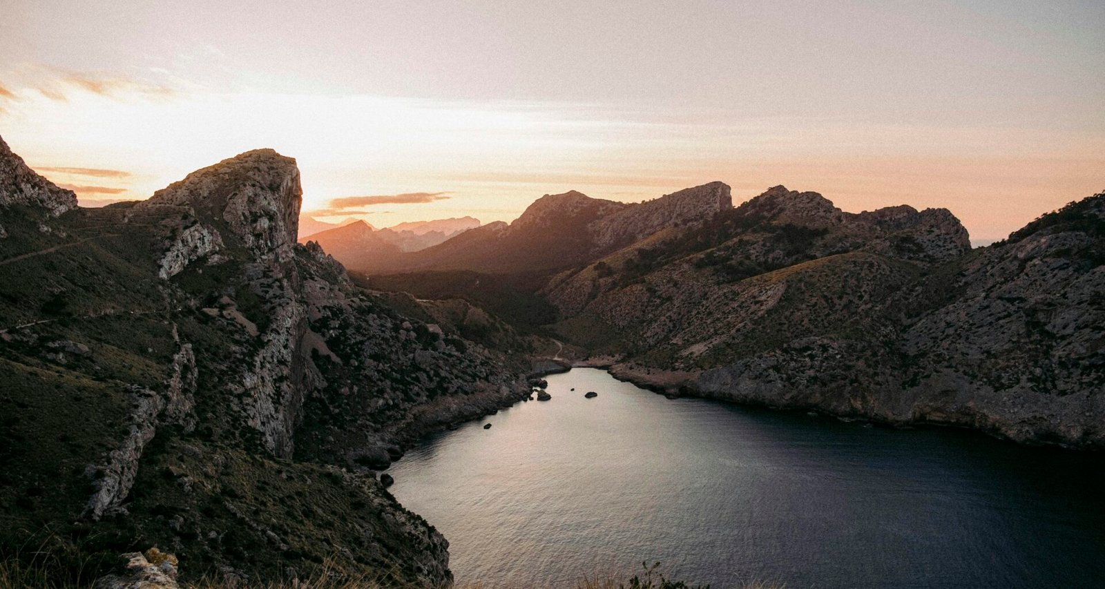 Ein ruhiges Gewässer mit Bergen im Hintergrund auf Mallorca, aufgenommen von Colin + Meg.