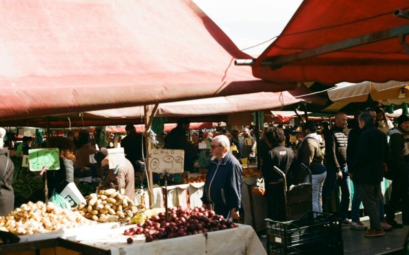 Gruppe von Menschen beim Einkaufen auf einem Markt auf Mallorca, Stände mit frischen Produkten