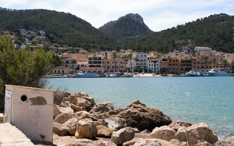 Szenische Ansicht eines Küstenstädtchens auf Mallorca am ruhigen Meer, aufgenommen von Tim Schmidbauer.