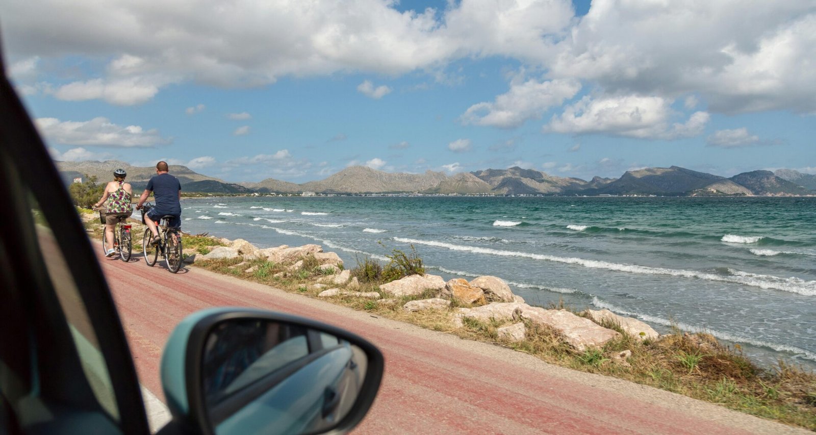 Mann in schwarzer Jacke und blauen Jeans steht am Seestrand auf Mallorca bei Tageslicht