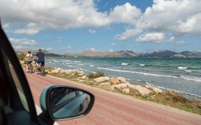 Mann in schwarzer Jacke und blauen Jeans steht am Seestrand auf Mallorca bei Tageslicht