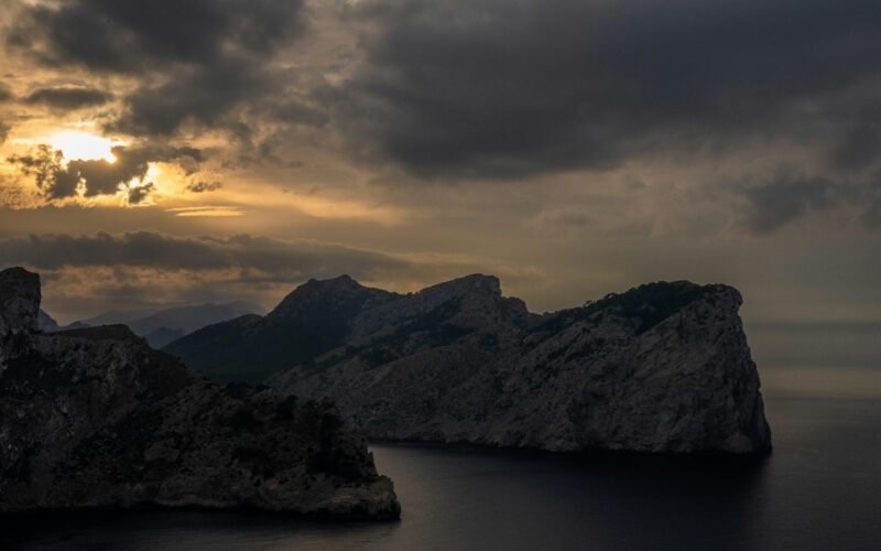 Felsige Küste auf Mallorca unter dunklem, stürmischem Sonnenuntergangshimmel, fotografiert von Tim Bernhard