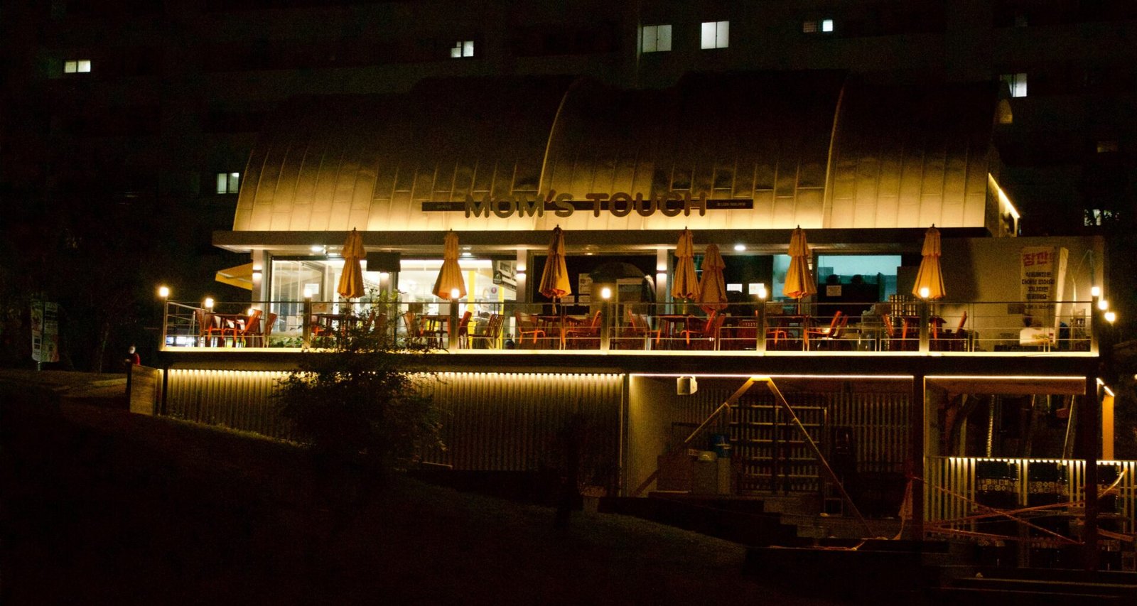 Ein beleuchtetes Restaurant am Flussufer auf Mallorca bei Nacht, mit warmem Licht und ruhiger Atmosphäre
