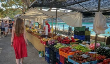 Frau läuft an Obst- und Gemüsehändlern auf Mallorca vorbei, lebendiger Markt mit frischen Produkten