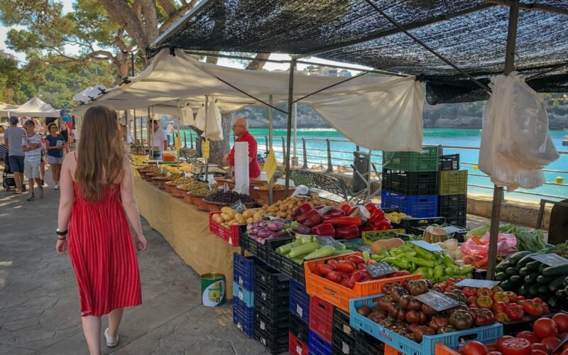 Frau läuft an Obst- und Gemüsehändlern auf Mallorca vorbei, lebendiger Markt mit frischen Produkten