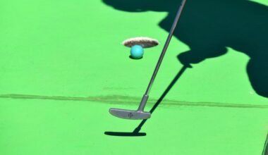 Person beim Golfabschlag auf Mallorca, Ball kurz vor dem Loch, im Hintergrund grüner Rasen
