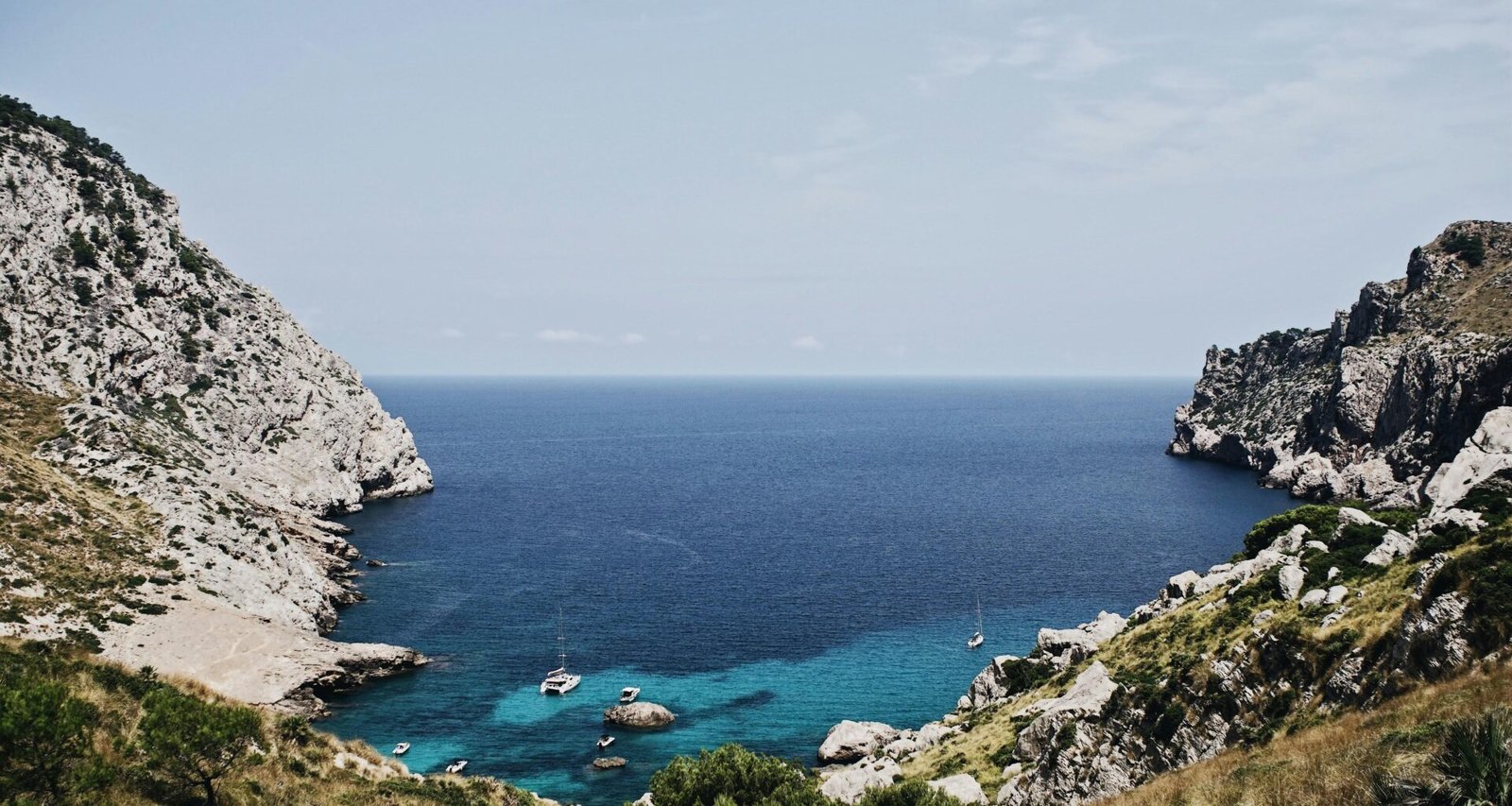 Boot liegt vor einer Insel auf Mallorca, fotografiert von Oscar Nord, mit klarem Wasser und ruhiger Umgebung