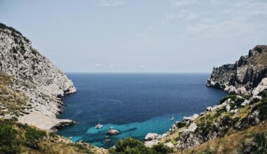 Boot liegt vor einer Insel auf Mallorca, fotografiert von Oscar Nord, mit klarem Wasser und ruhiger Umgebung
