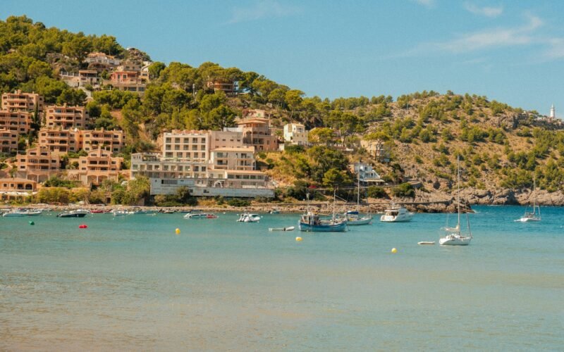 Boote in einer Bucht auf Mallorca mit Gebäuden an der Küste im Hintergrund, aufgenommen von Alexis Presa.
