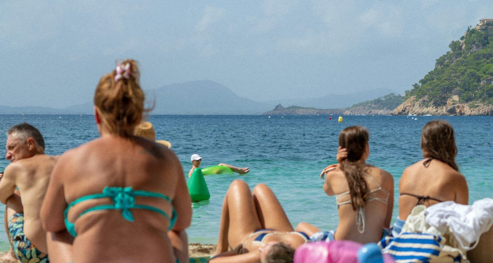 Menschen liegen entspannt auf einem Strand auf Mallorca und genießen den Blick aufs Meer, fotografiert von Victor Rosario.