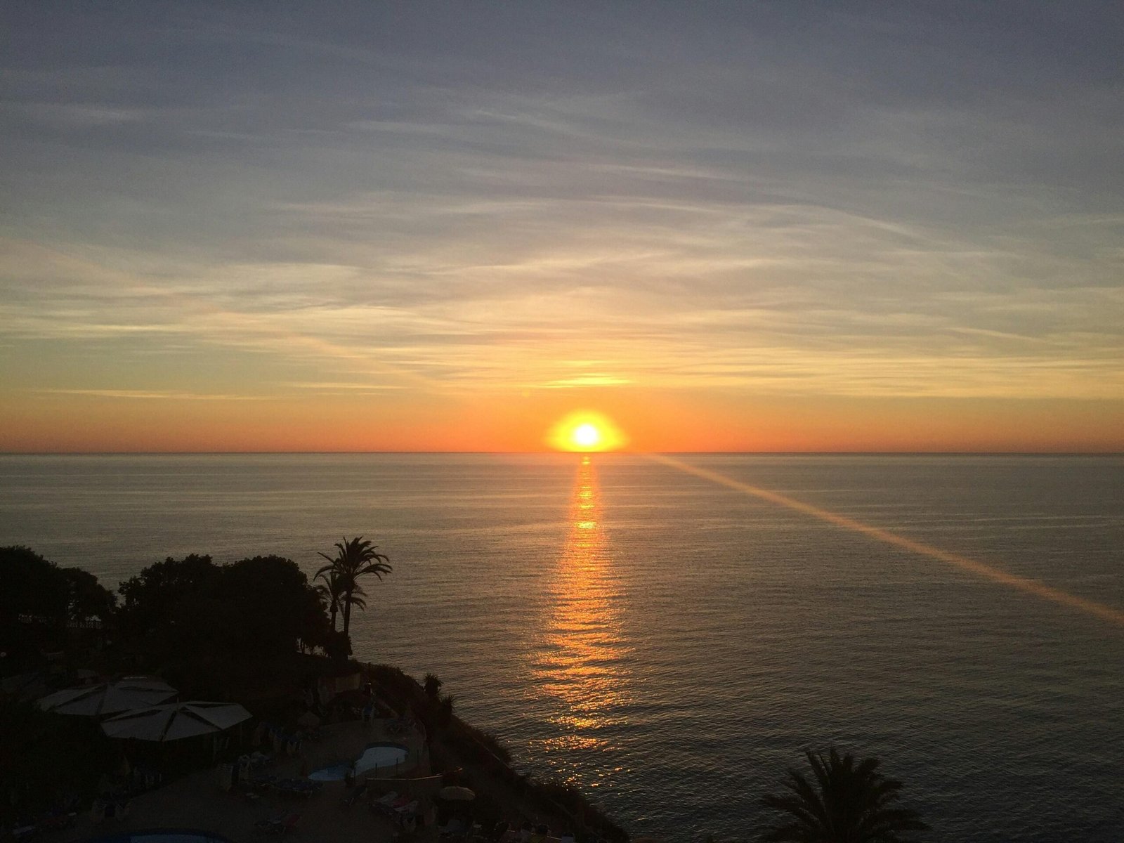 Sonnenuntergang über dem Meer auf Mallorca mit Palmen im Vordergrund, aufgenommen von Chris Everiss