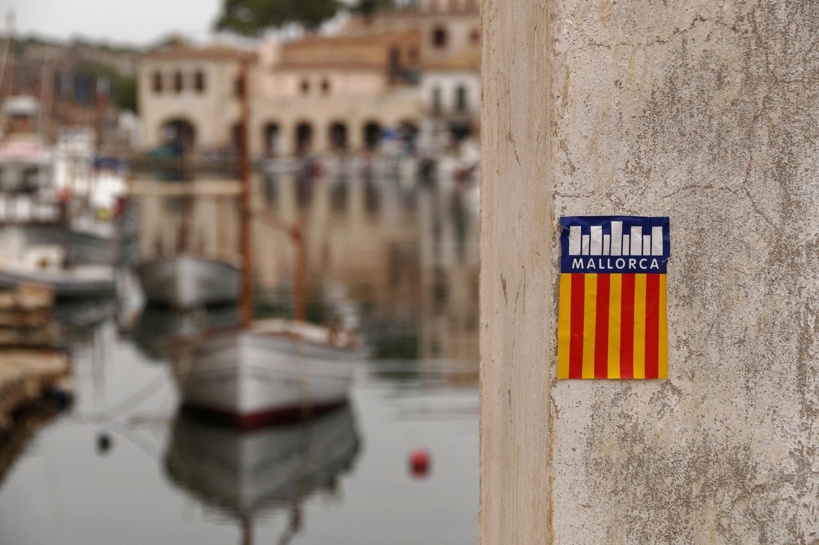 Sticker an einer Wand nahe einem Hafen auf Mallorca, aufgenommen von Alex Kulikov