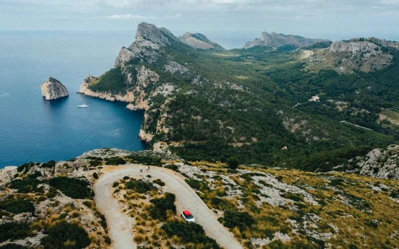 Ein Auto fährt auf Mallorca auf einer Straße in der Nähe von Bergen, aufgenommen von Austin Farrington.