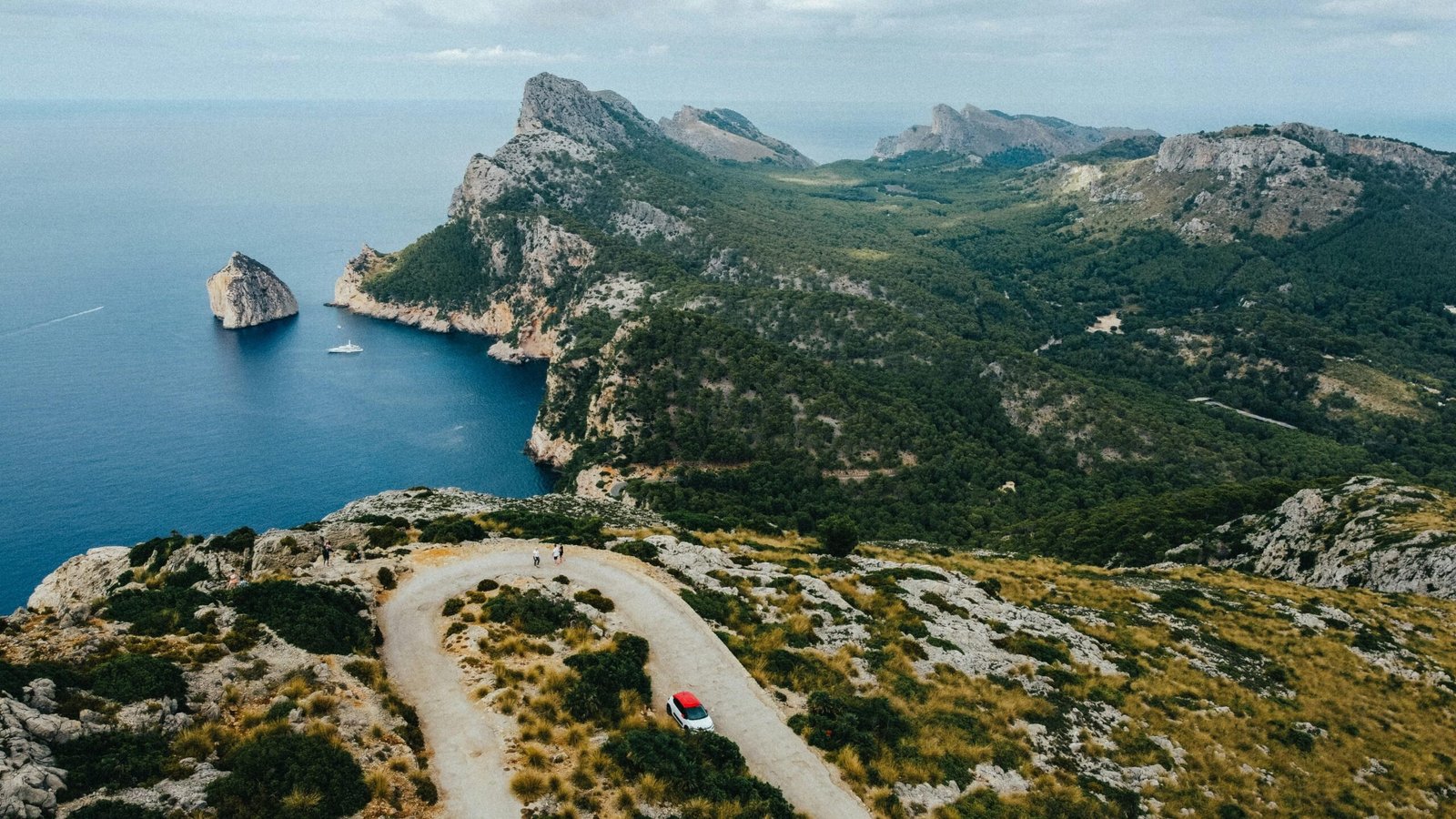 Ein Auto fährt auf Mallorca eine Straße entlang, umgeben von Bergen und Natur, aufgenommen von Austin Farrington.