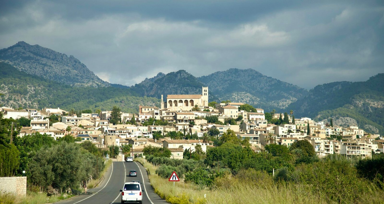 Ein Auto fährt auf Mallorca auf einer Straße mit Stadt im Hintergrund, aufgenommen von Stock Birken.