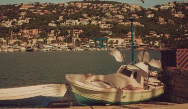 Ein Boot liegt am Ufer eines Sees auf Mallorca, aufgenommen von Raymond Petrik, mit ruhigem Wasser und Naturkulisse.
