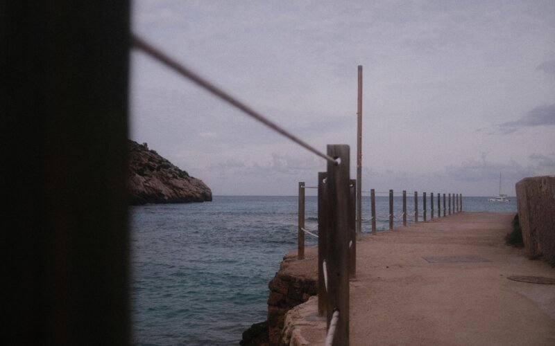 Ein Gehweg mit Geländer entlang der Küste auf Mallorca, Blick auf das Meer im Hintergrund, fotografiert von Marius Matuschzik.