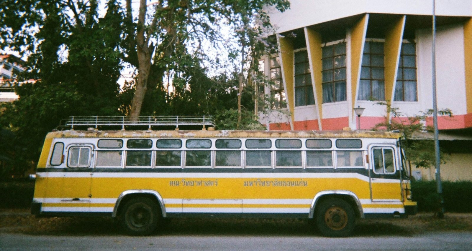 Gelber und weißer Bus parkt vor einem Gebäude auf Mallorca, fotografiert von narue sri