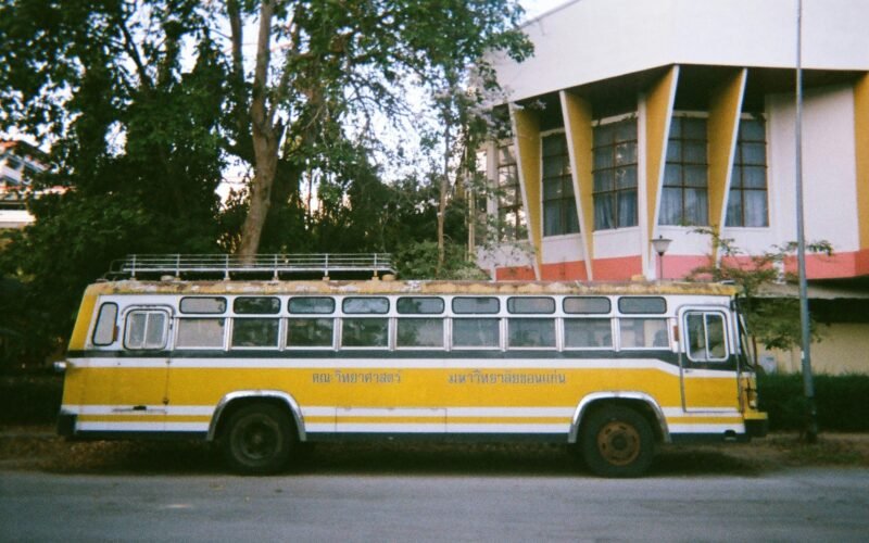 Gelber und weißer Bus parkt vor einem Gebäude auf Mallorca, fotografiert von narue sri