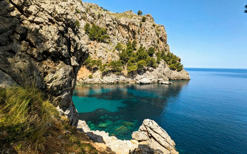 Klares Wasser vor einer felsigen Klippe auf Mallorca, aufgenommen von Andre Blanco, zeigt die natürliche Küstenlandschaft.