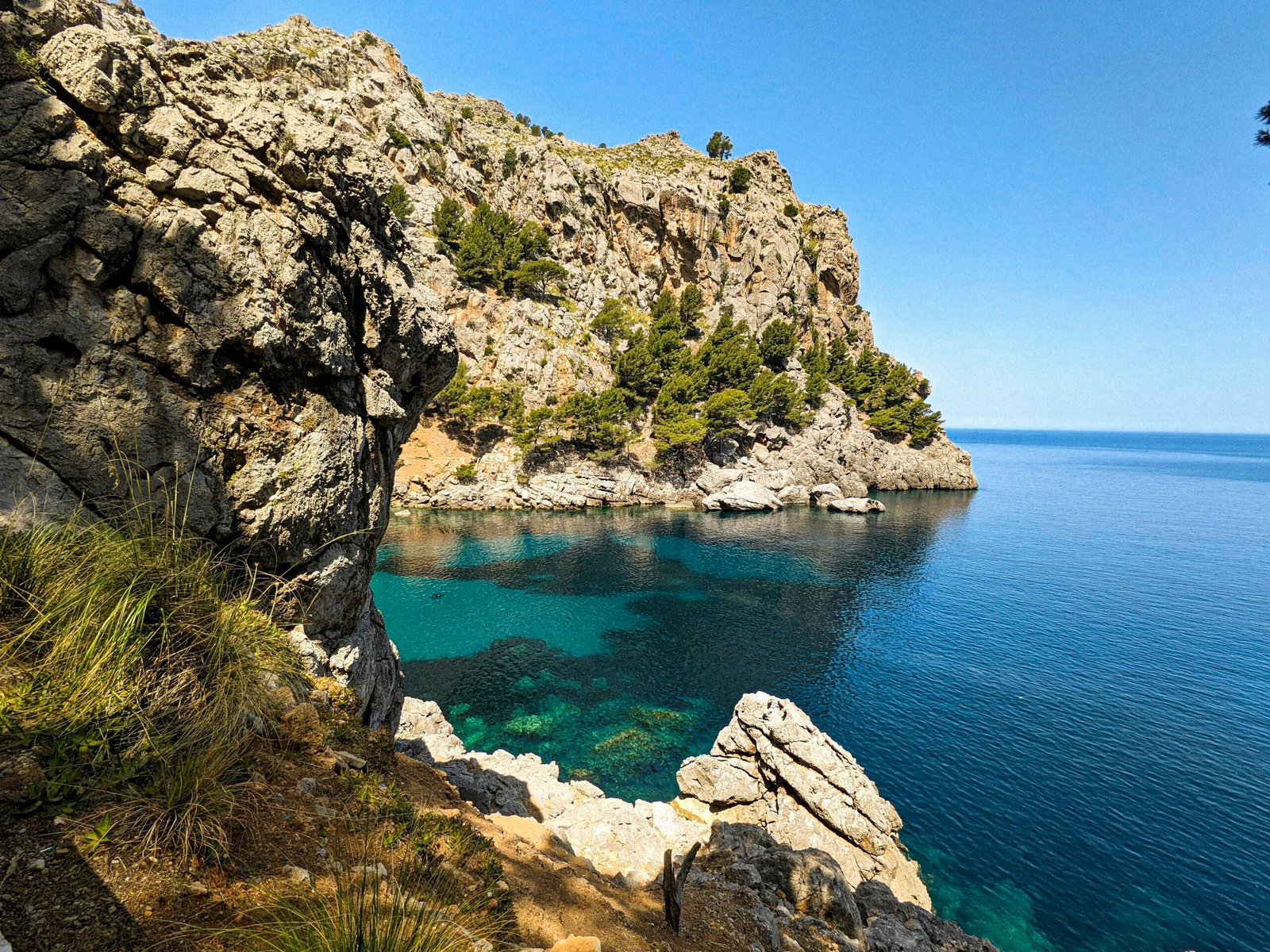 Klares Wasser vor einer felsigen Klippe auf Mallorca, aufgenommen von Andre Blanco, zeigt die natürliche Küstenlandschaft.