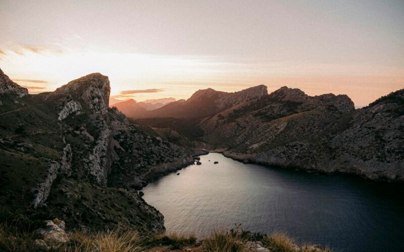 Ein ruhiges Gewässer mit Bergen im Hintergrund auf Mallorca, aufgenommen von Colin + Meg.