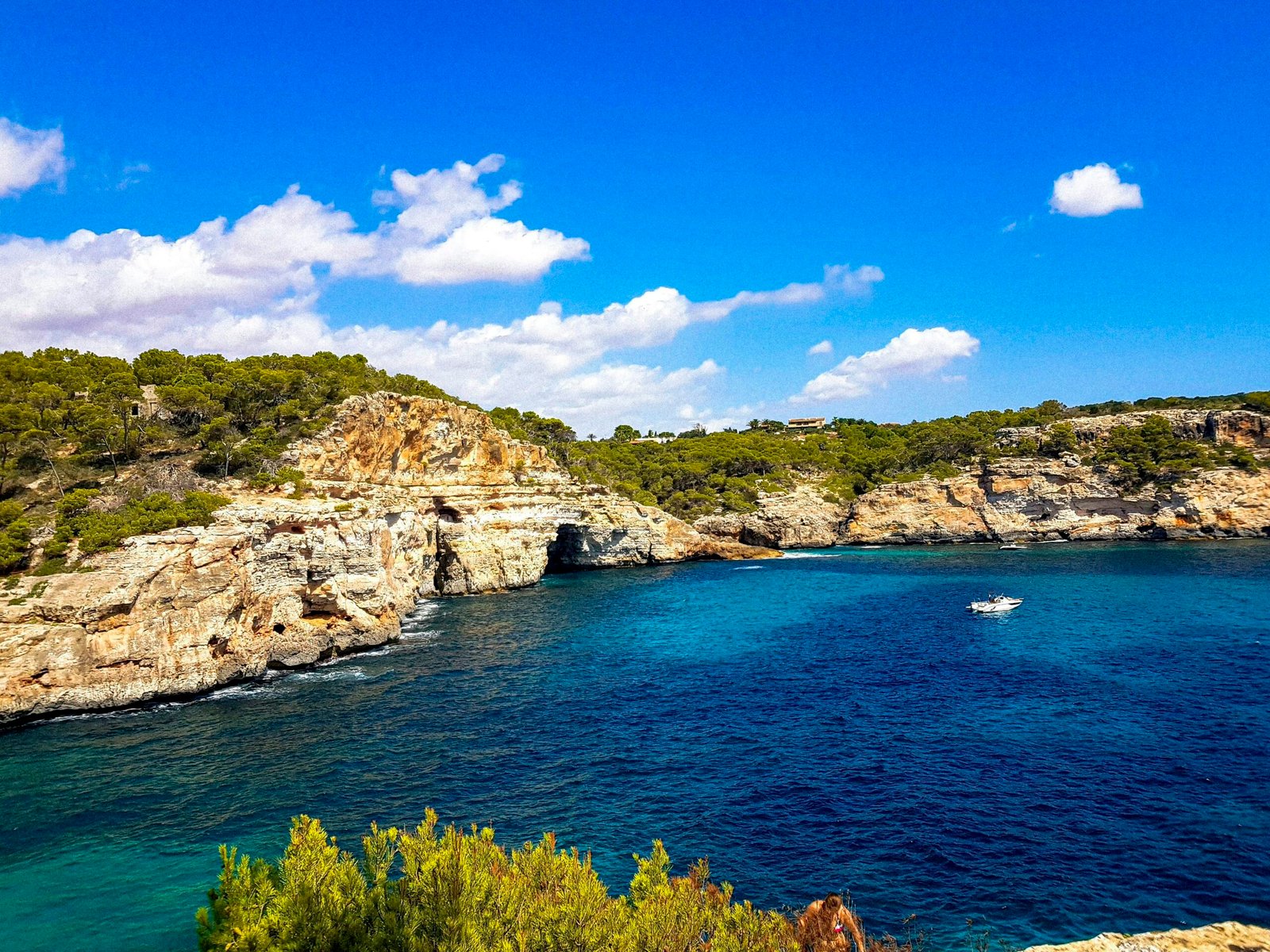 Ein Boot schwimmt auf einem ruhigen Wasser auf Mallorca, umgeben von einer weiten Wasserfläche und Himmel