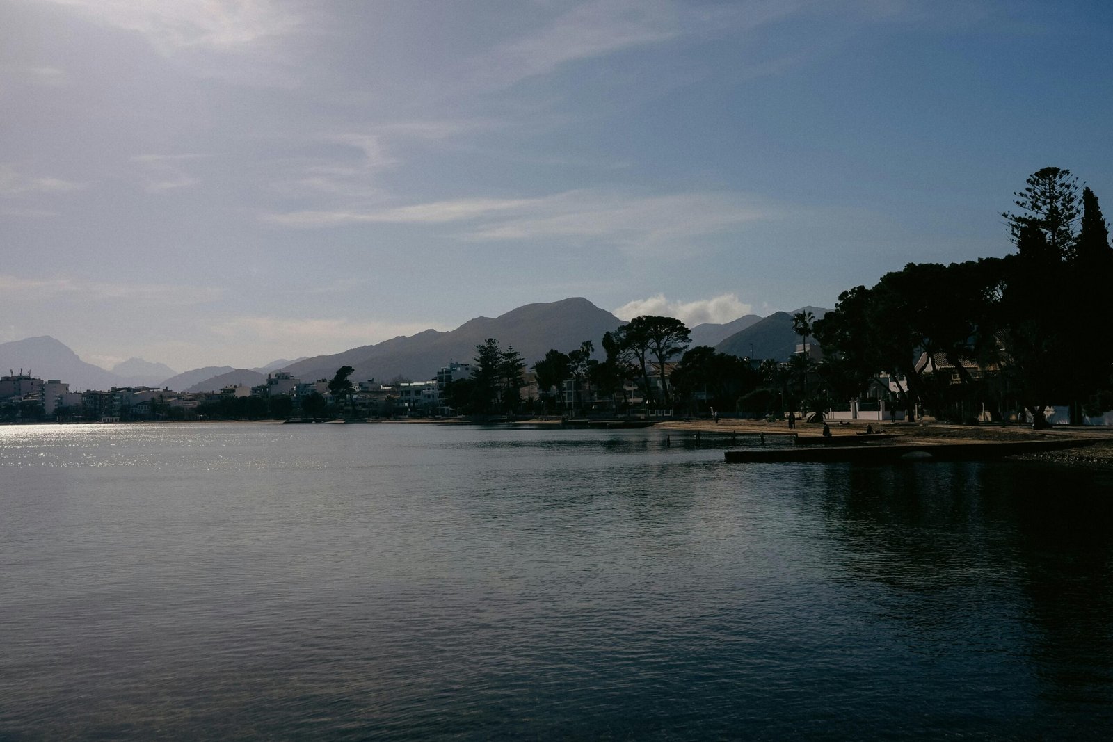 Ein Gewässer auf Mallorca, umgeben von Bäumen und Bergen, aufgenommen von Konstantin Chemeris.