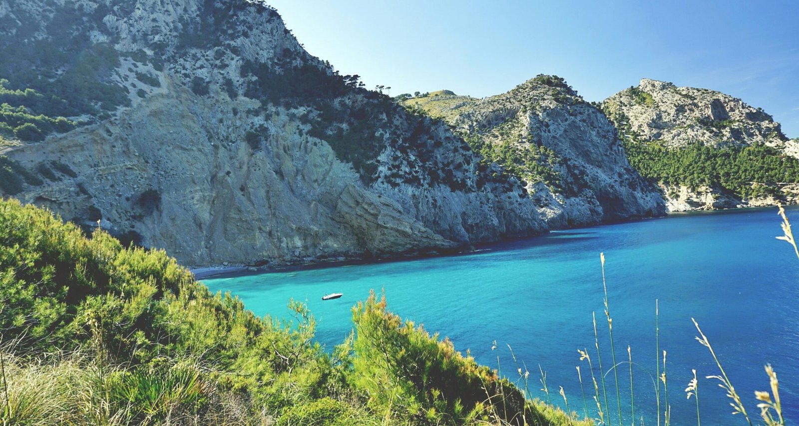 Ein ruhiger Wasserlauf auf Mallorca, umgeben von Bergen und grünen Wiesen, aufgenommen von Tom Lorber