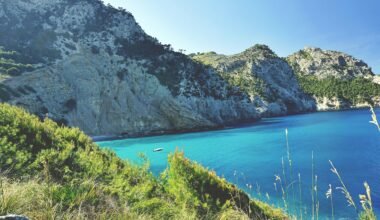 Ein ruhiger Wasserlauf auf Mallorca, umgeben von Bergen und grünen Wiesen, aufgenommen von Tom Lorber