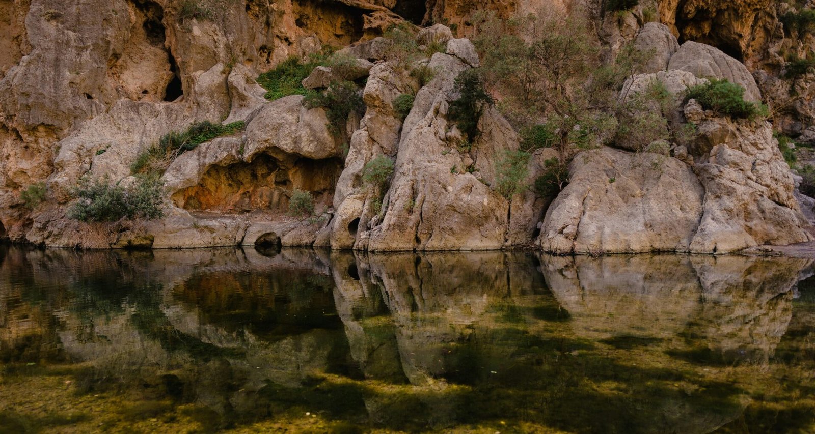 Ein Gewässer auf Mallorca, umgeben von Felsen und Gras, aufgenommen von Mariya, zeigt die ruhige Natur der Insel.
