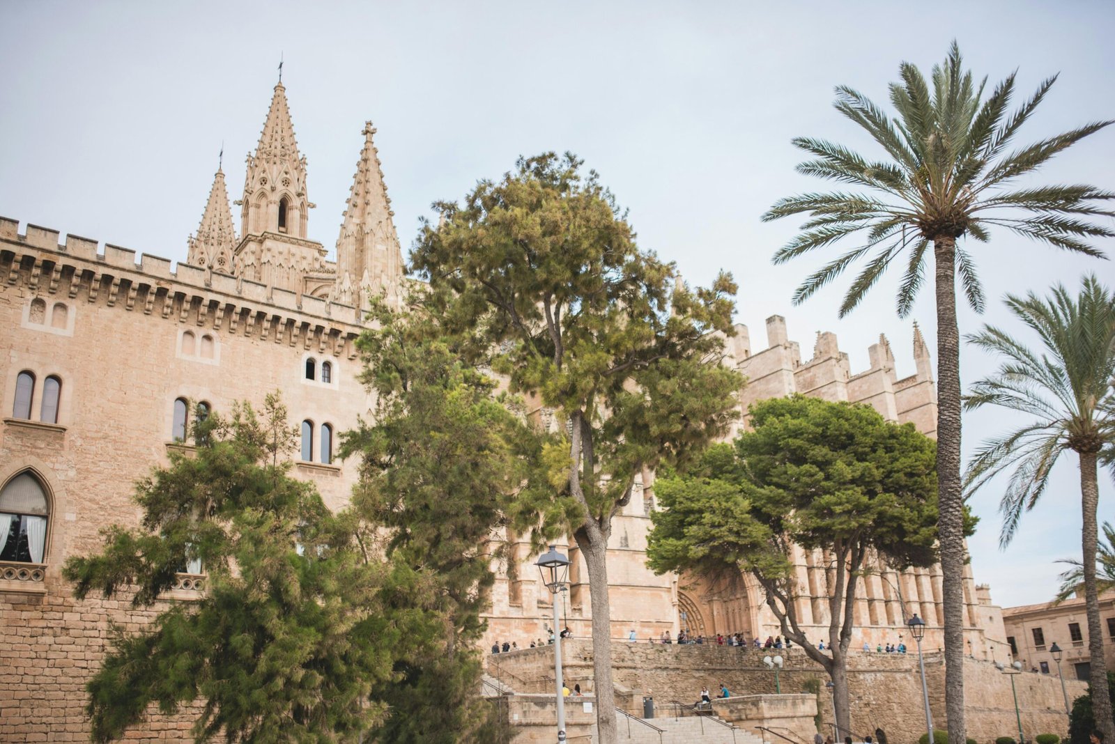Großes Gebäude mit hohem Turm und umgebenden Bäumen auf Mallorca, fotografiert von Monika Guzikowska.
