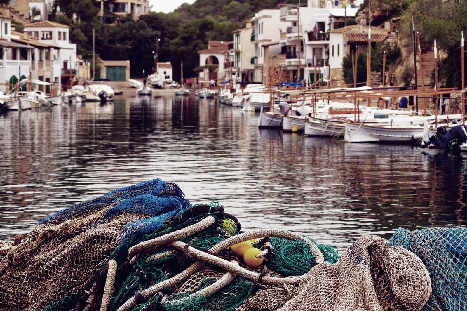 Mehrere Boote liegen in ruhigem Wasser in einer Bucht auf Mallorca, fotografiert von Alex Kulikov.