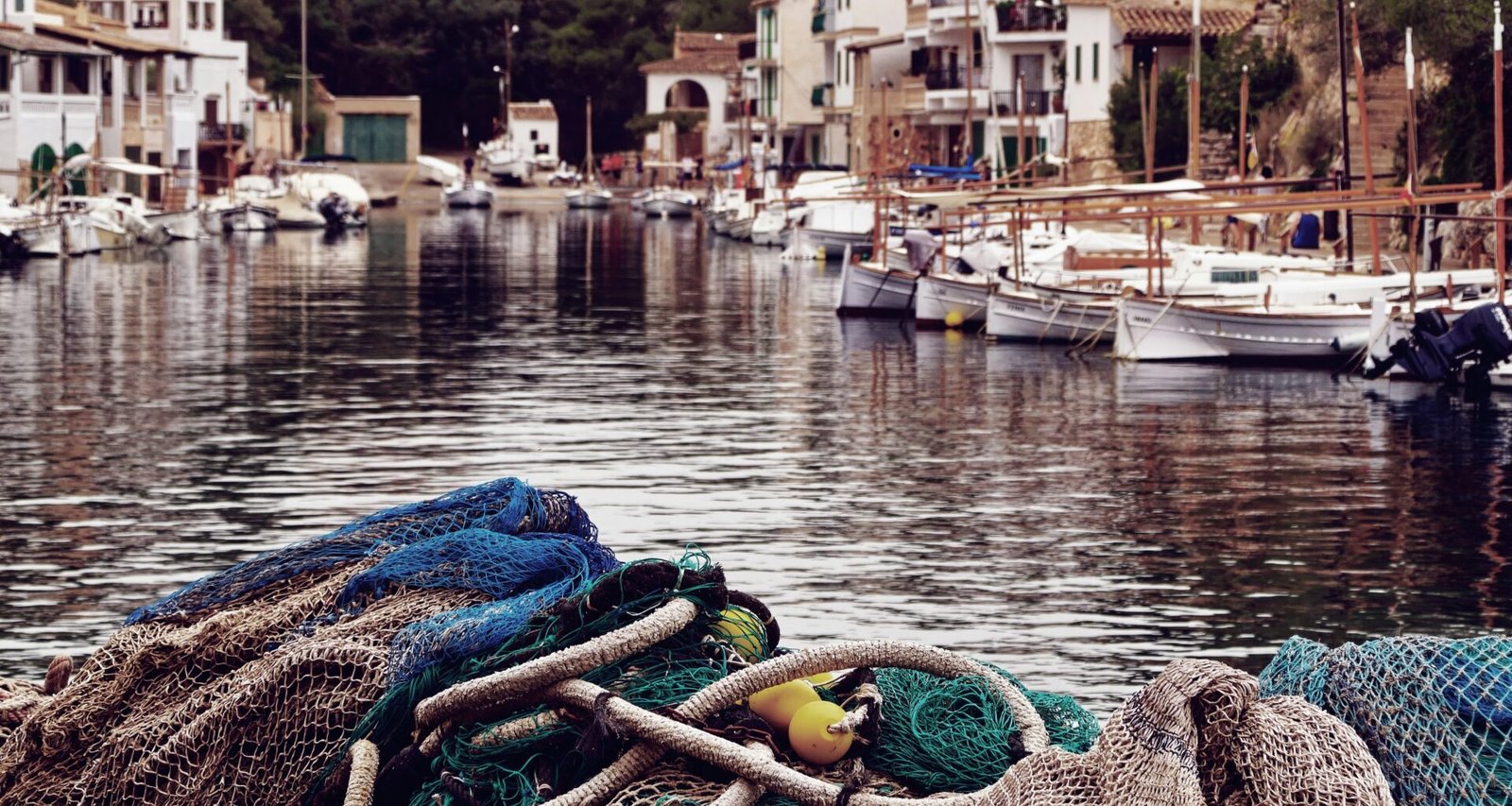 Mehrere Boote ruhen im Wasser auf Mallorca, fotografiert von Alex Kulikov.