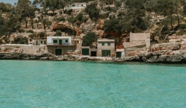 Ein Haus auf einer Klippe auf Mallorca mit Blick auf das Wasser im Hintergrund, fotografiert von Shery Arturova.