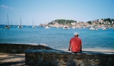 Mann sitzt auf Mallorca auf einer Mauer und blickt auf das Wasser, die Küste im Hintergrund, aufgenommen von Nick Page.