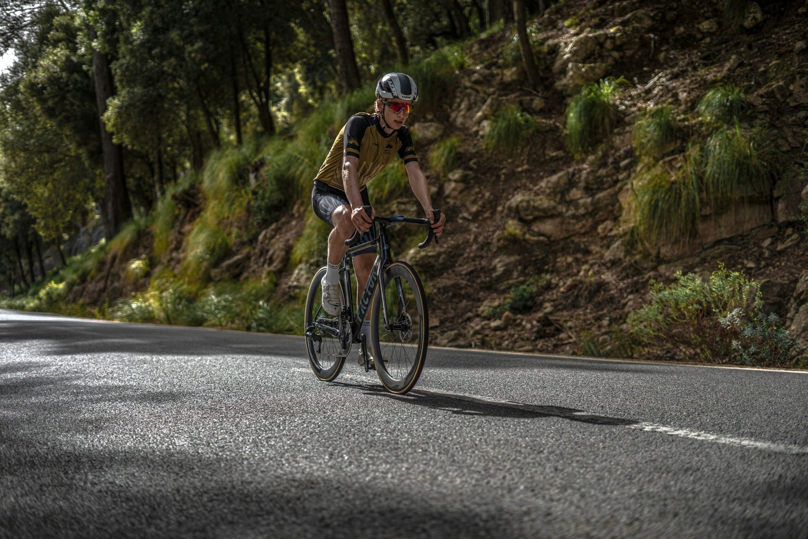 Mann fährt mit dem Fahrrad auf einer Straße auf Mallorca, umgeben von Natur und Landschaft.
