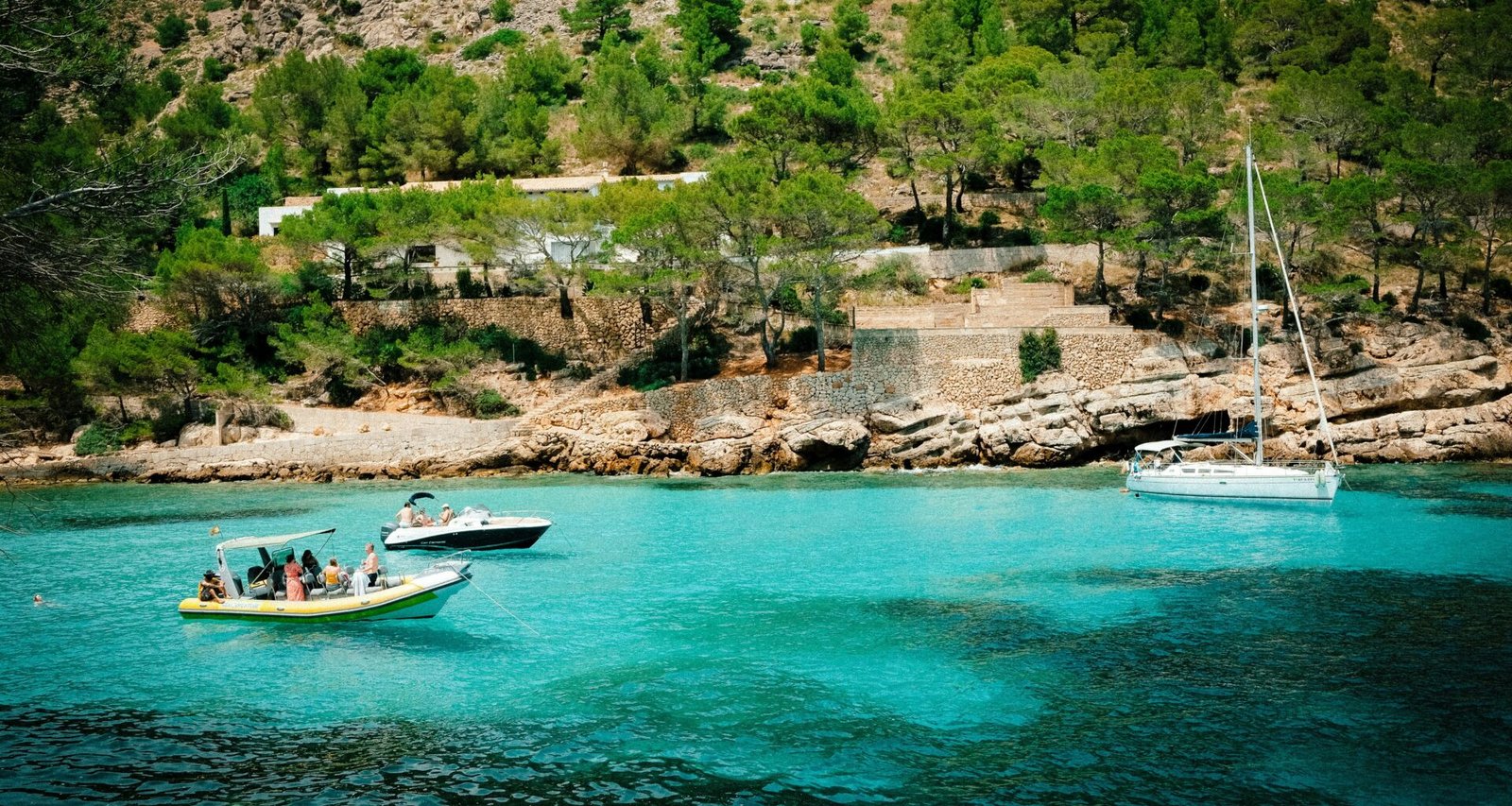 Mehrere Boote liegen im Wasser auf Mallorca, fotografiert von Luke Moss.