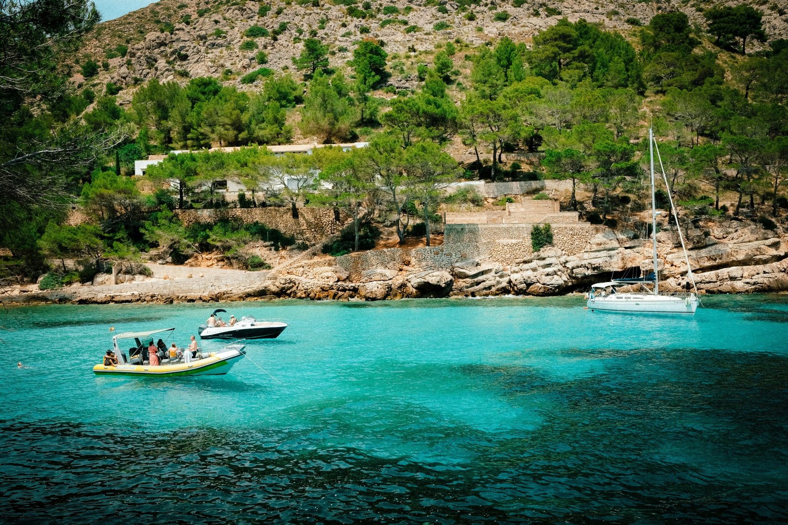 Mehrere Boote liegen im Wasser auf Mallorca, fotografiert von Luke Moss.