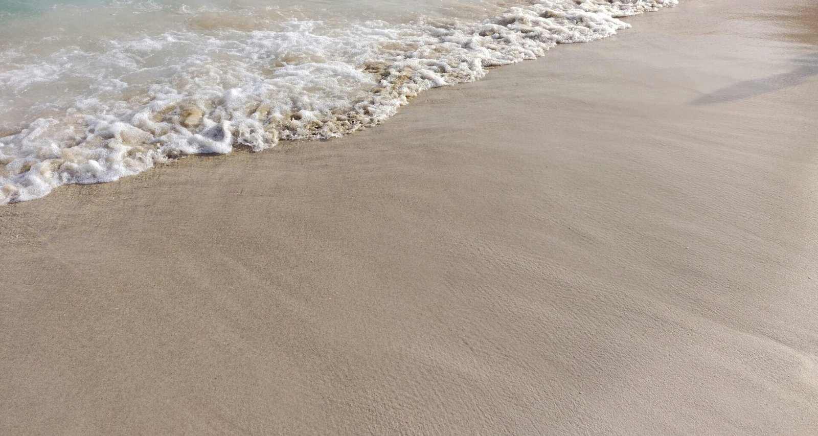 Sandstrand auf Mallorca mit Wellen, aufgenommen von Mauro Leoni, zeigt die Küstenlinie und das Meer