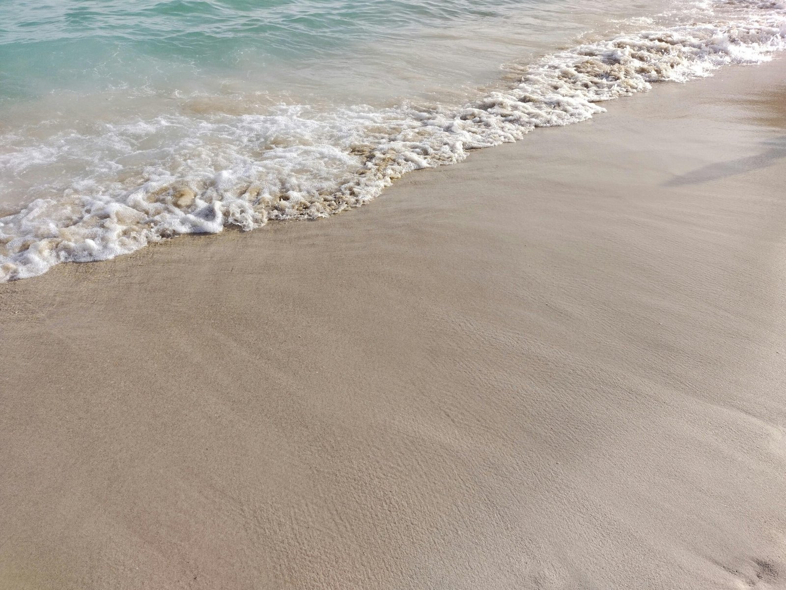 Sandstrand auf Mallorca mit Wellen, aufgenommen von Mauro Leoni, zeigt die Küstenlinie und das Meer