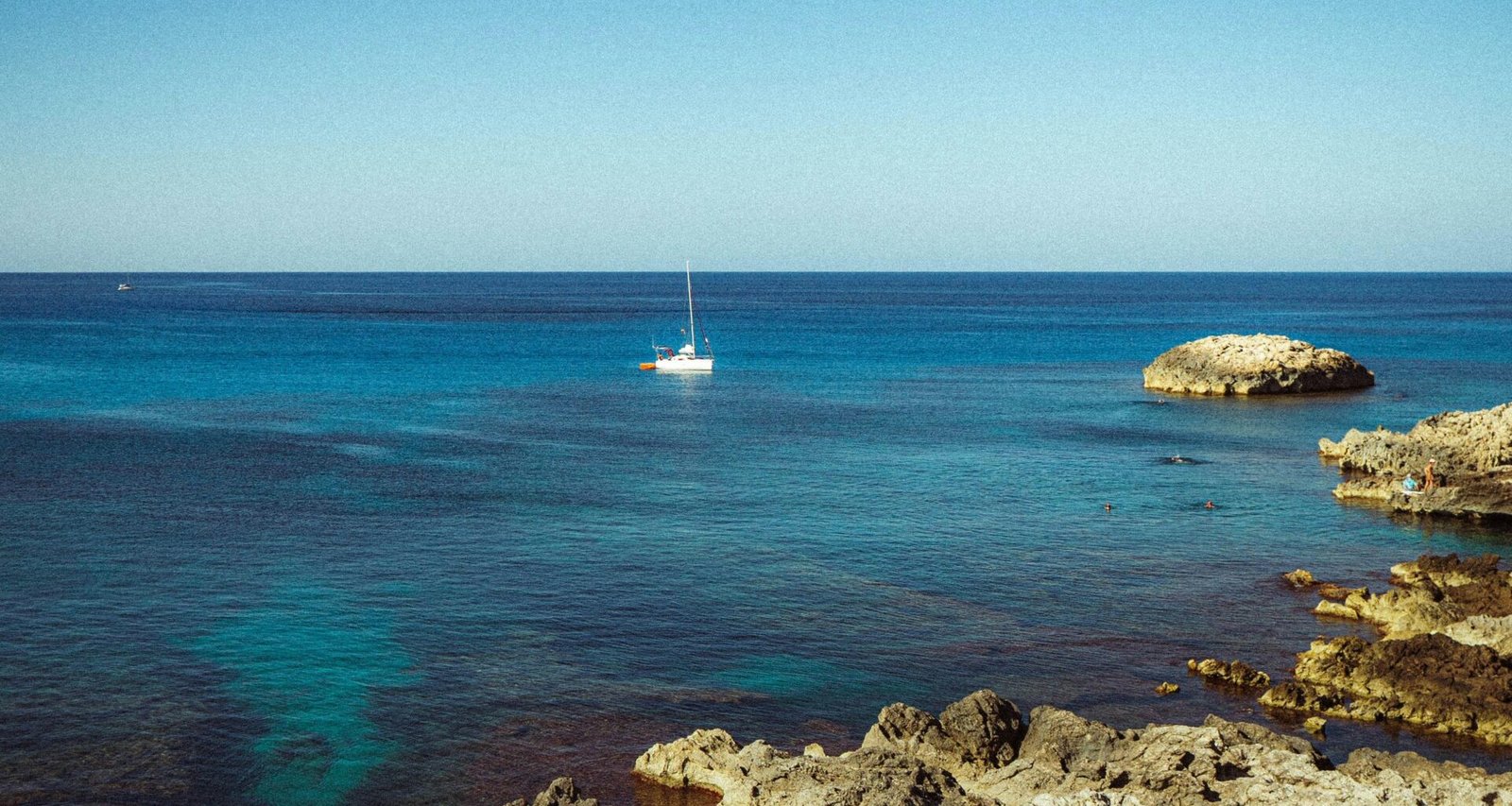Segelboot driftet auf Mallorca im klaren, türkisfarbenen Meer, aufgenommen von Polina Cherkasova.