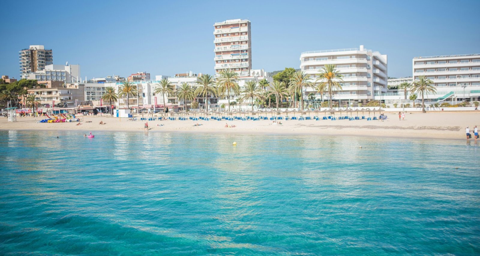 Strand auf Mallorca mit Gebäuden im Hintergrund, aufgenommen von Monika Guzikowska