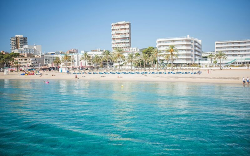 Strand auf Mallorca mit Gebäuden im Hintergrund, aufgenommen von Monika Guzikowska