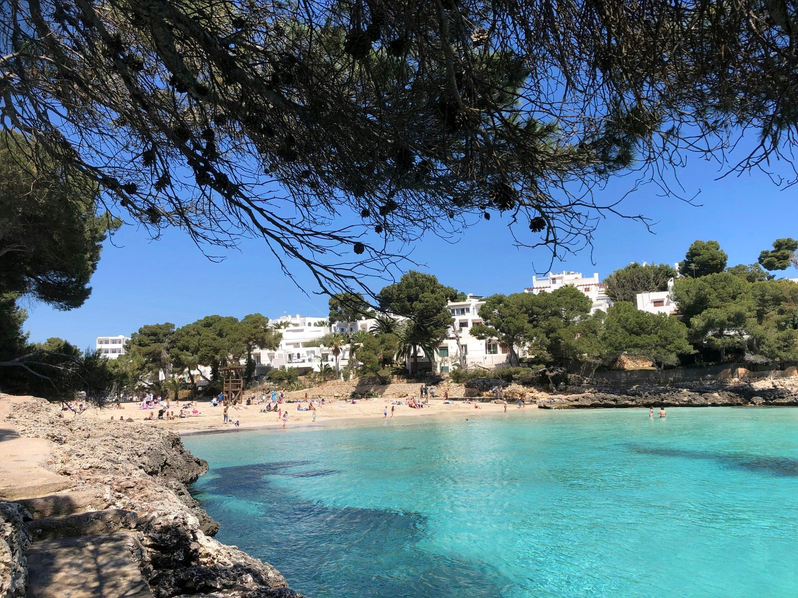 Ein Strand auf Mallorca mit Menschen, die am Wasser liegen und die Sonne genießen, fotografiert von yelr.