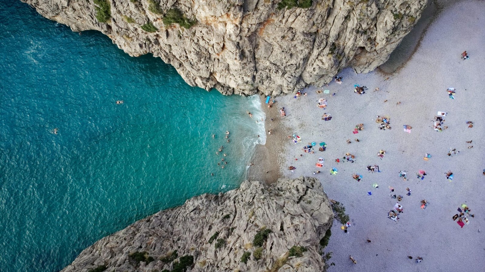 Menschen schwimmen im klaren Wasser an einem Strand auf Mallorca, Sonnenliegen und Strandatmosphäre sichtbar, aufgenommen von Alex Kulikov