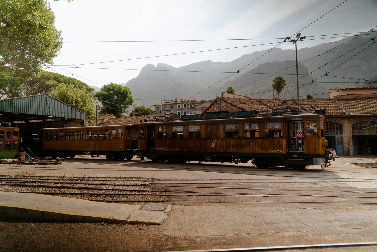Ein Zug fährt an einem Bahnhof vorbei mit Bergen im Hintergrund auf Mallorca, aufgenommen von Victor Oonk.