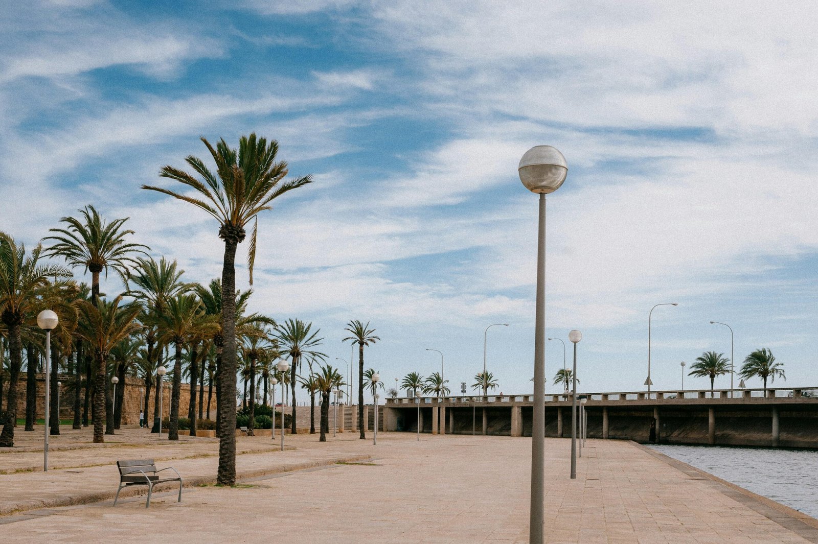 Eine Bank sitzt neben einem Wasser auf Mallorca, aufgenommen von Julian, ideal für entspannte Pausen.